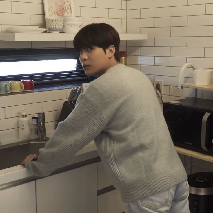 a young man is washing dishes in the kitchen