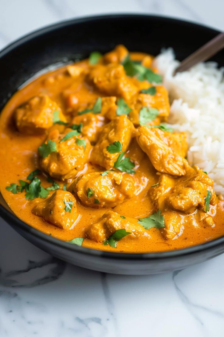 a black bowl filled with rice and chicken curry