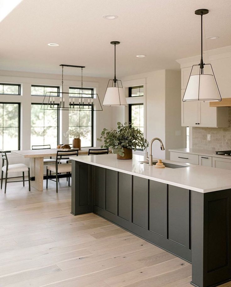 a large kitchen with an island in the middle and two pendant lights hanging from the ceiling