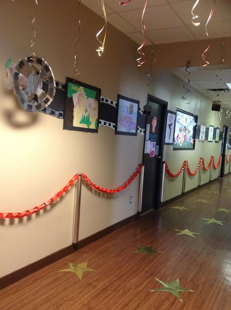 an office hallway decorated with paper stars and streamers hanging from the ceiling, along with pictures on the walls