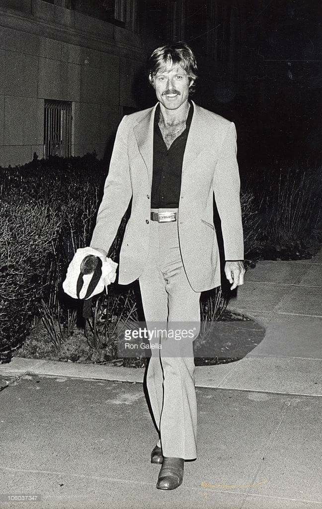 black and white photograph of man in suit walking down sidewalk