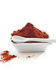 a white bowl filled with red powder next to a spoon full of ground cinnamons