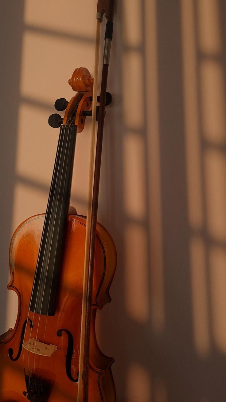 an orange violin leaning against a wall with the sun shining on it's side