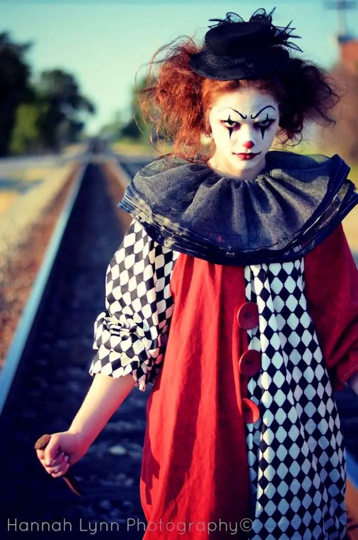 a woman dressed as a clown walking down train tracks