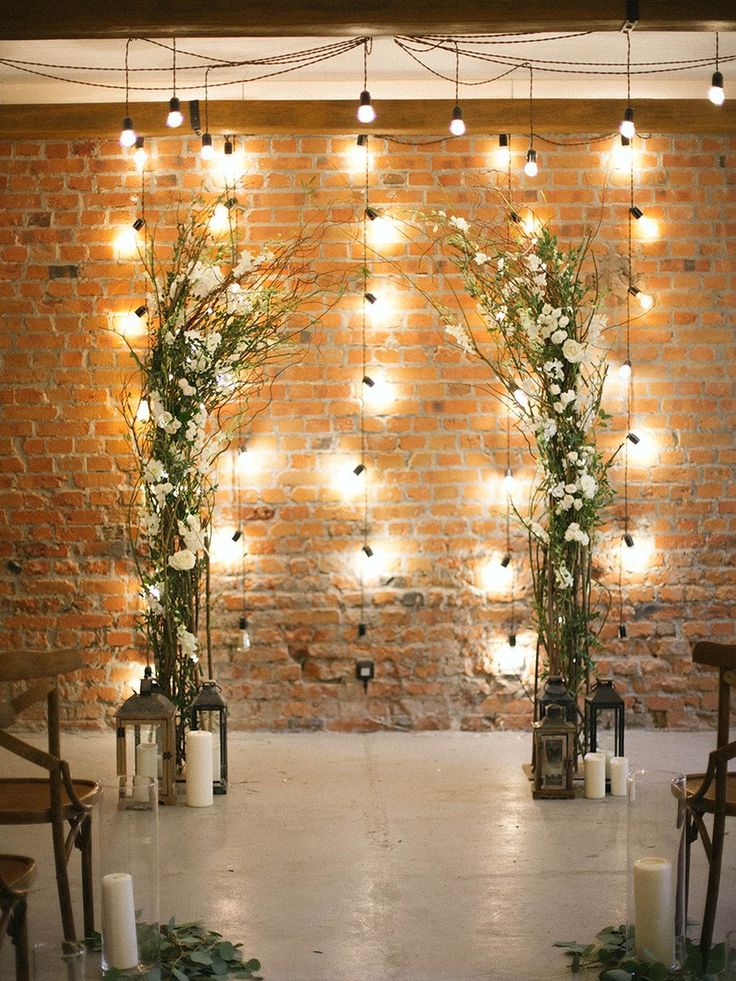 an indoor wedding setup with candles and greenery on the floor, surrounded by brick walls