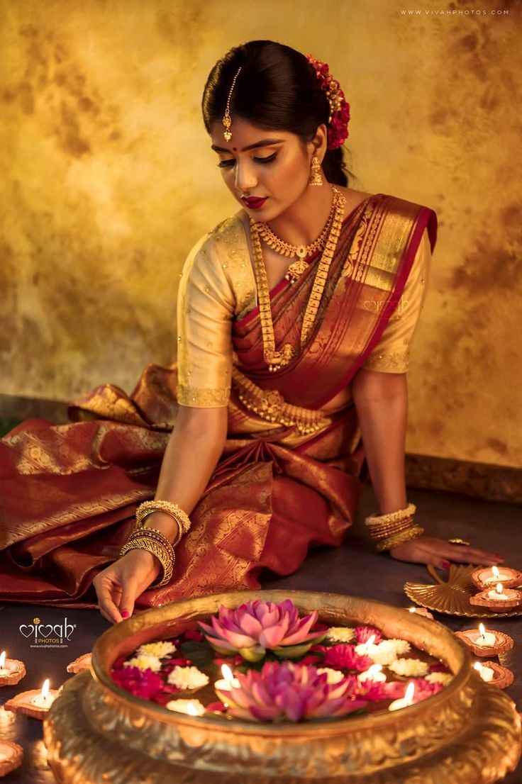 a woman sitting on the ground in front of a plate with flowers and lit candles