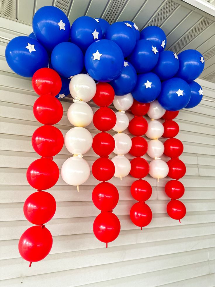 red, white and blue balloons are hanging from the ceiling