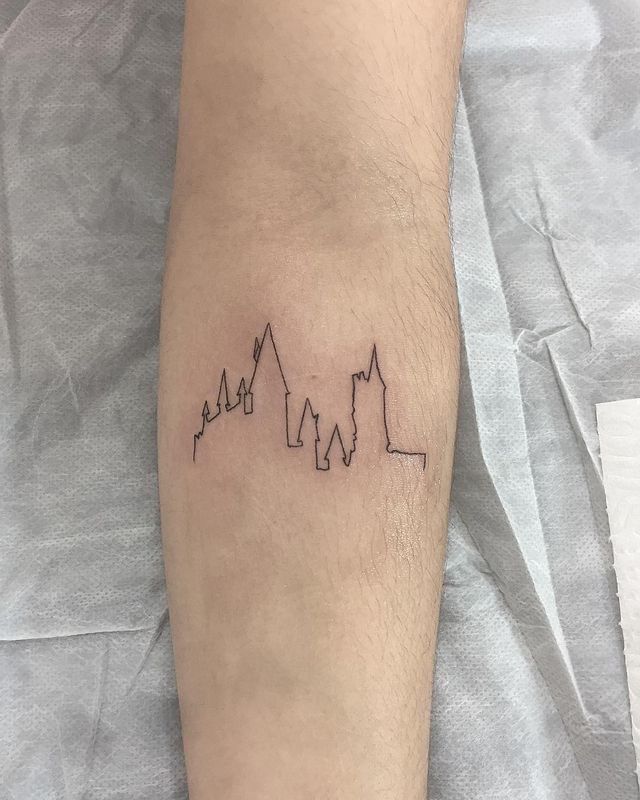 a man with a tattoo on his leg that has three buildings in the shape of mountains