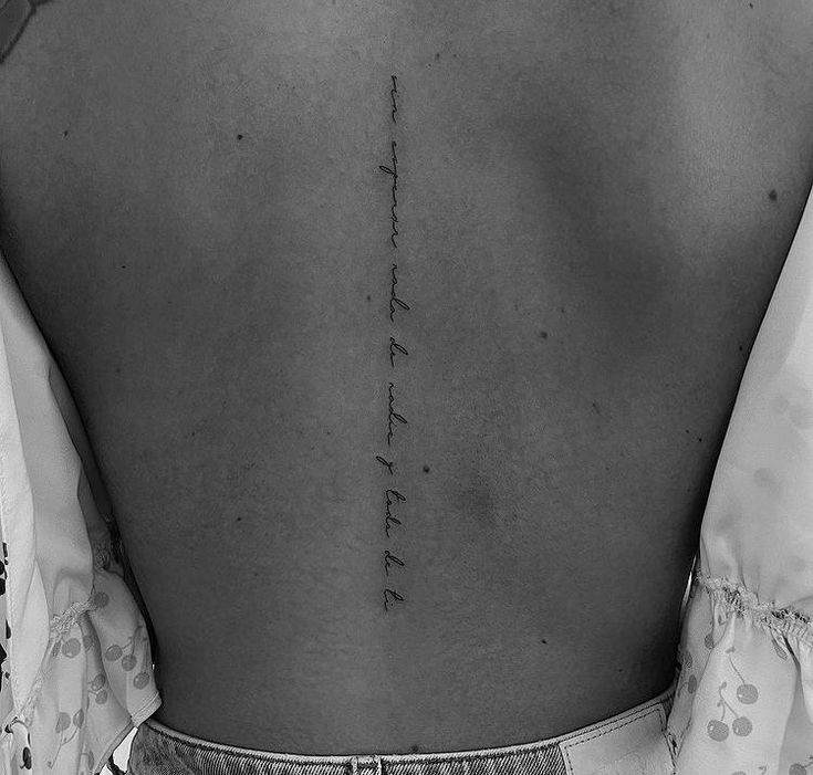 the back of a woman's lower back tattoo with words written in cursive writing