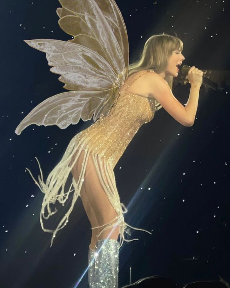 a woman dressed as a fairy holding a microphone in front of a stage with stars