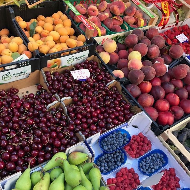 many different fruits are on display at the grocery store, including plums, apples, pears and blueberries