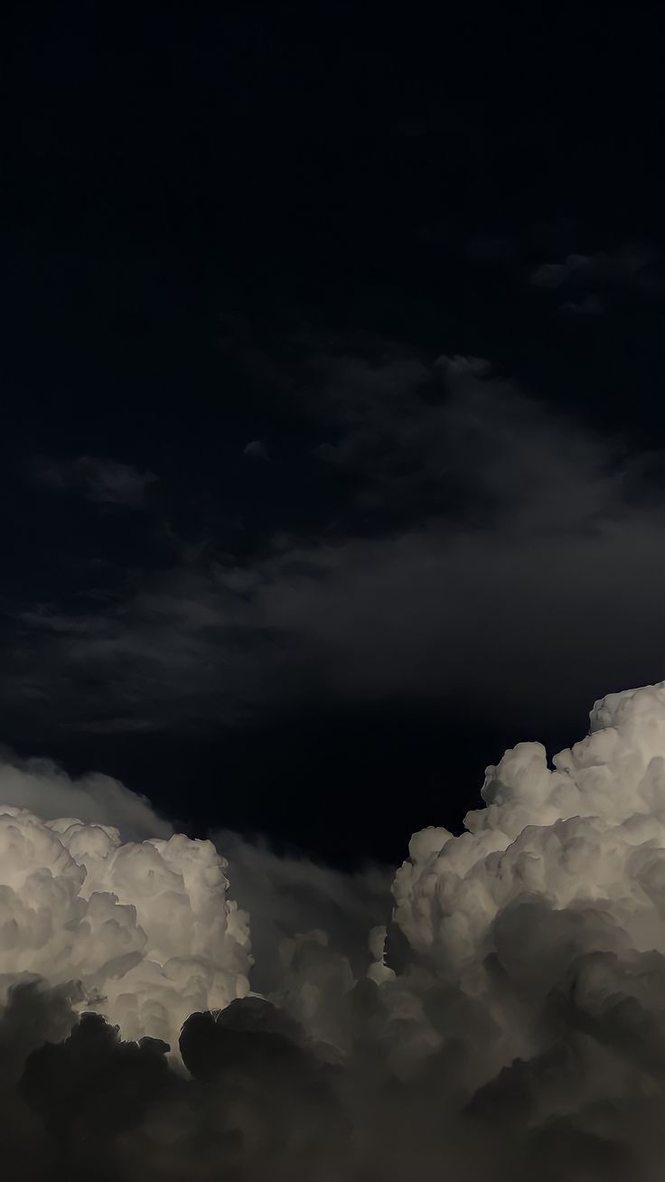 an airplane is flying high in the sky with clouds around it and dark skies above