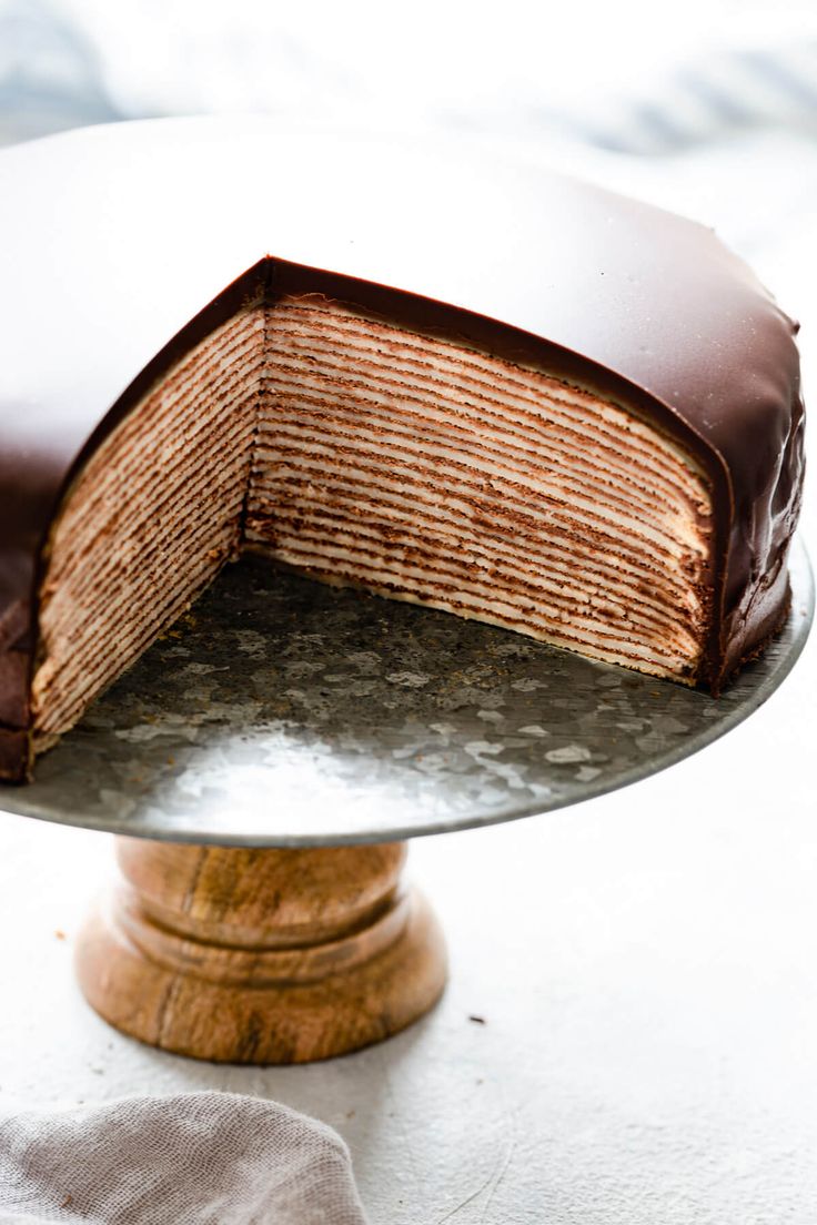 a chocolate cake on a silver platter with one slice cut out and ready to be eaten