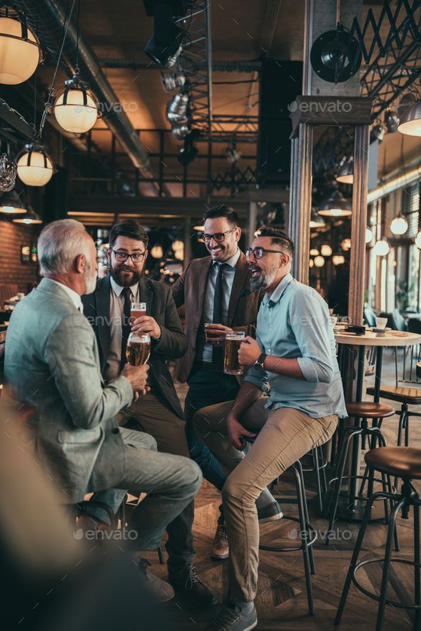 three men sitting at a bar talking to each other and drinking beer in front of them