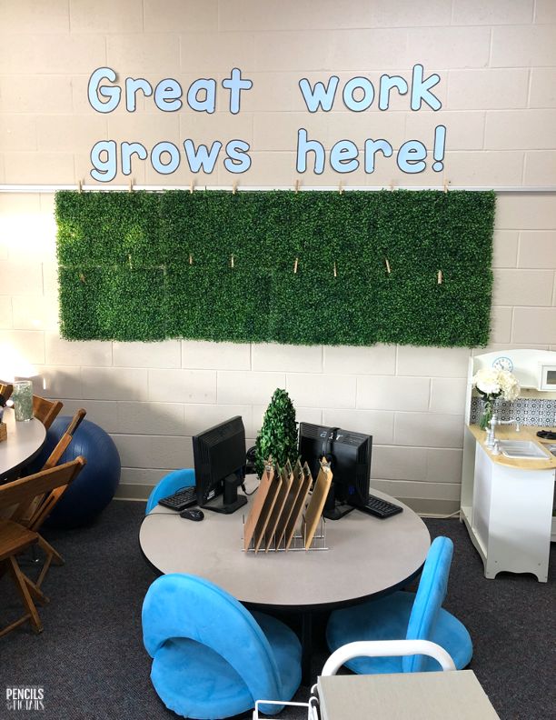 an office cubicle with chairs, desks and a green wall behind it that says great work grows here