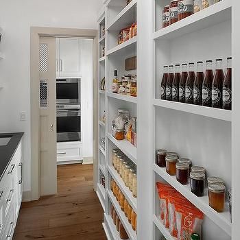 a kitchen with white cabinets and shelves filled with jars, spices and condiments