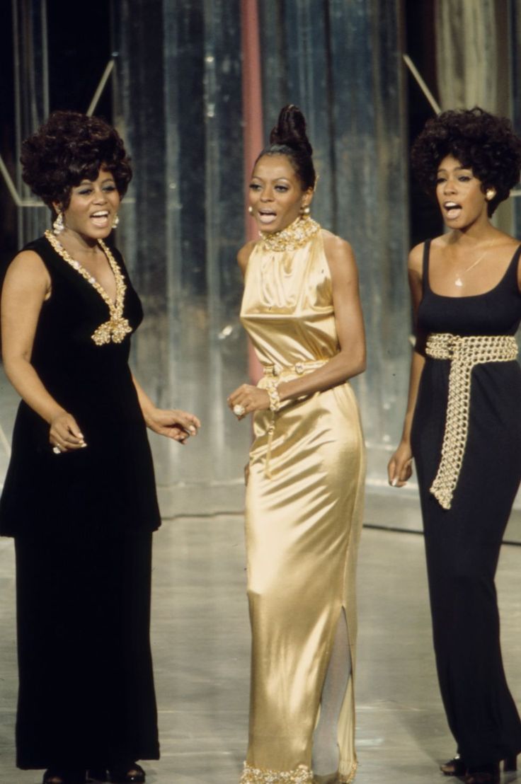 three women standing next to each other in formal wear and one is wearing a gold dress