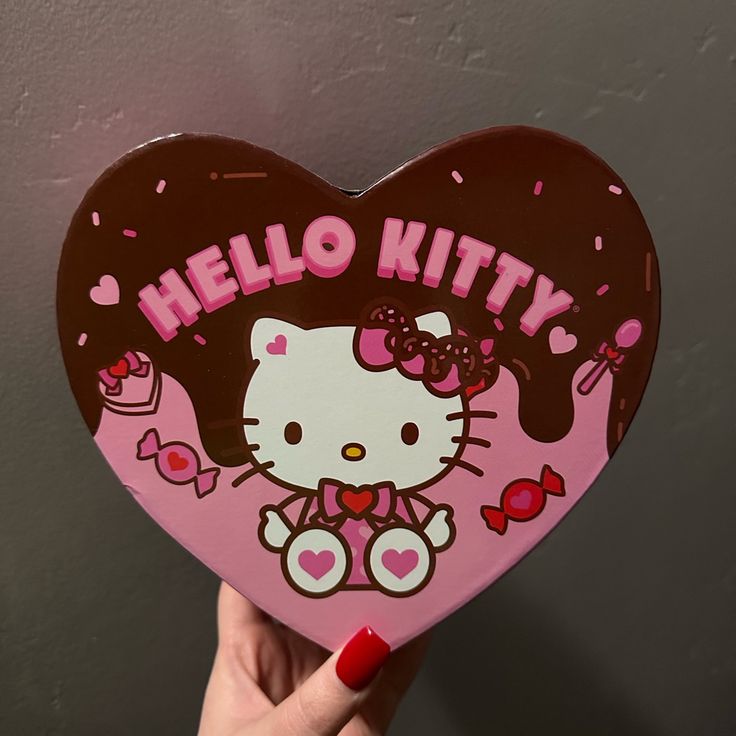 someone holding up a hello kitty heart shaped box with the word hello kitty on it