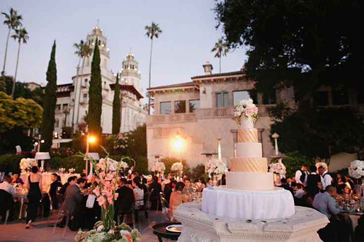 a large wedding cake on top of a table in front of a group of people