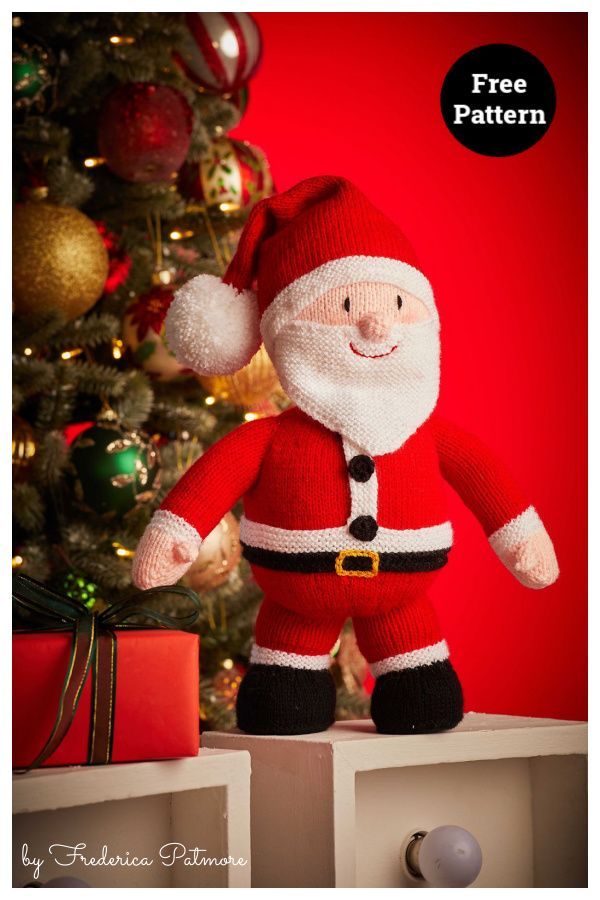 a knitted santa clause doll sitting on top of a table next to a christmas tree