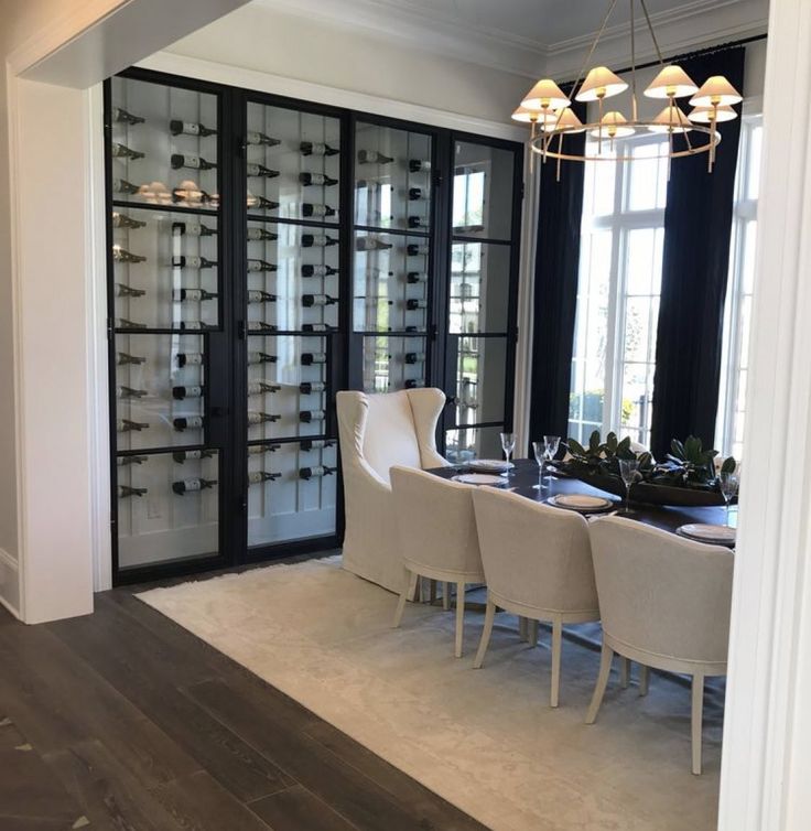 the dining room table is set with white chairs, and there are many wine glasses on display behind it