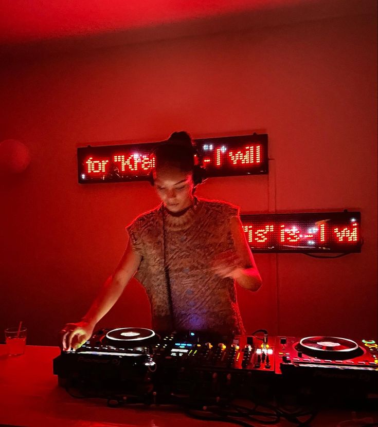 a man that is standing in front of a dj's turntable with lights on