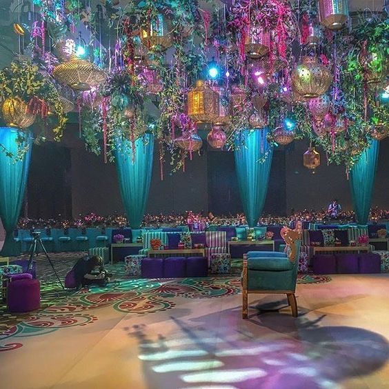 an elaborately decorated room with chandeliers and chairs in the center is lit by colorful lights