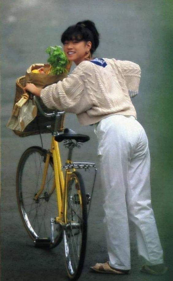 a woman standing next to a yellow bike with a bag on it's back