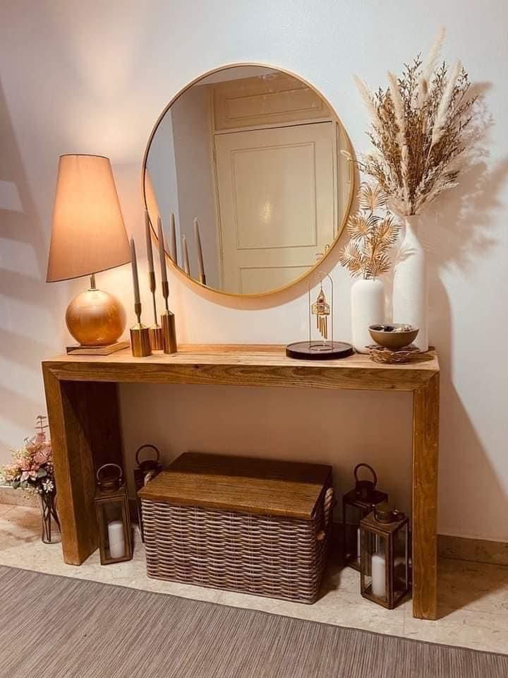 a wooden table topped with a mirror next to a lamp