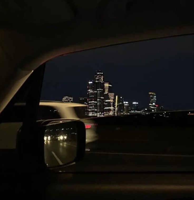 the view from inside a car at night with city lights in the background