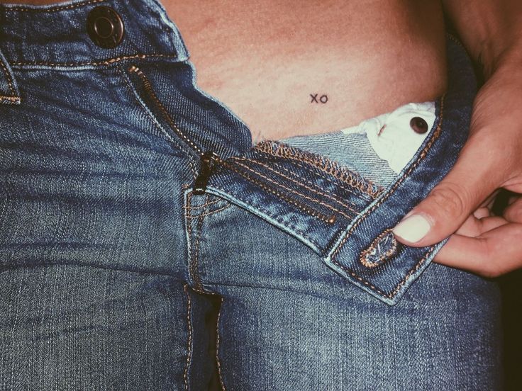 a person is holding their stomach in the pocket of his jean pants, which has an x on it