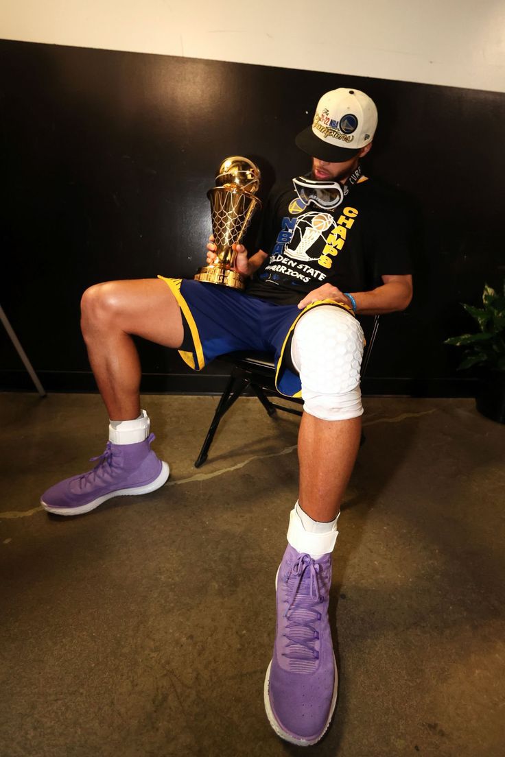 a young man sitting in a chair with his foot up on the soccer ball and holding a trophy