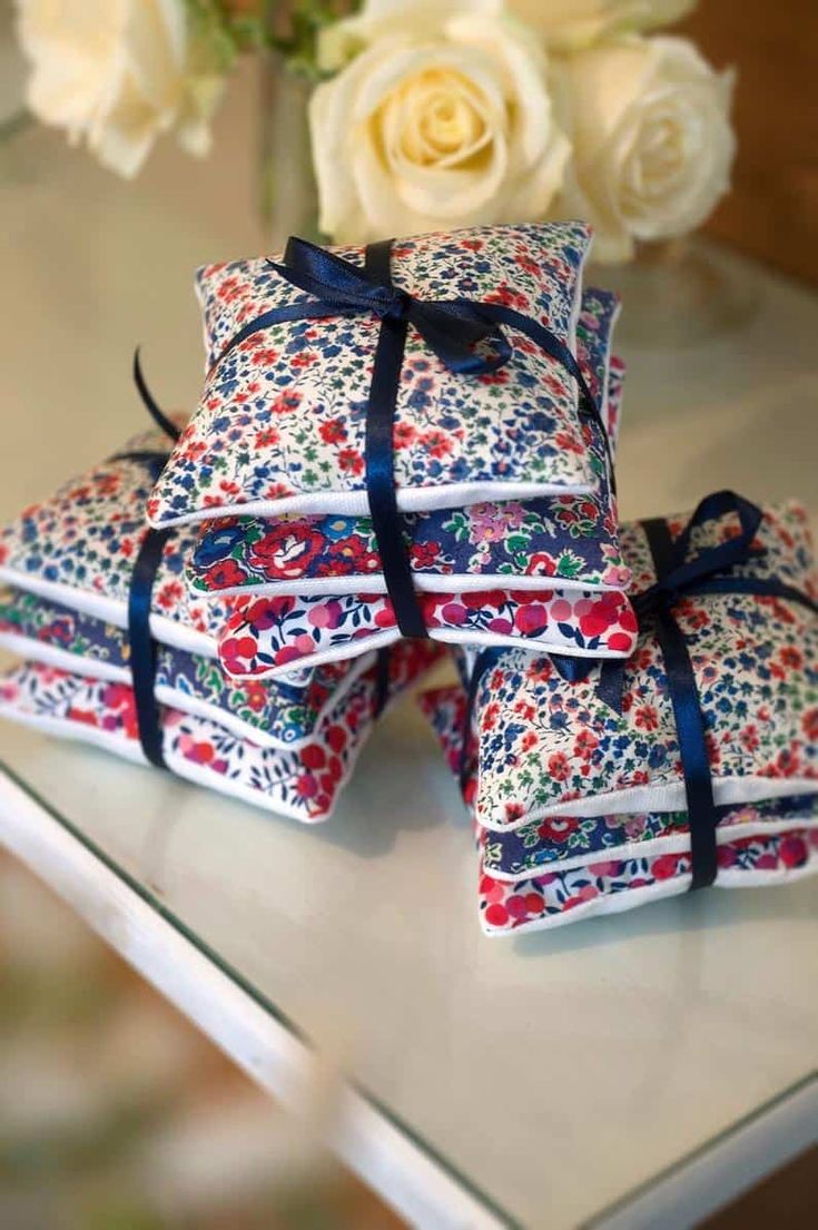 a stack of cloths sitting on top of a table next to a vase filled with flowers