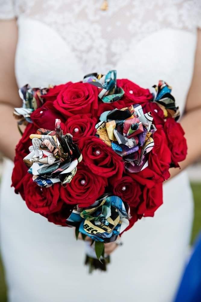 a bridal holding a bouquet of red roses and brooches in her hands