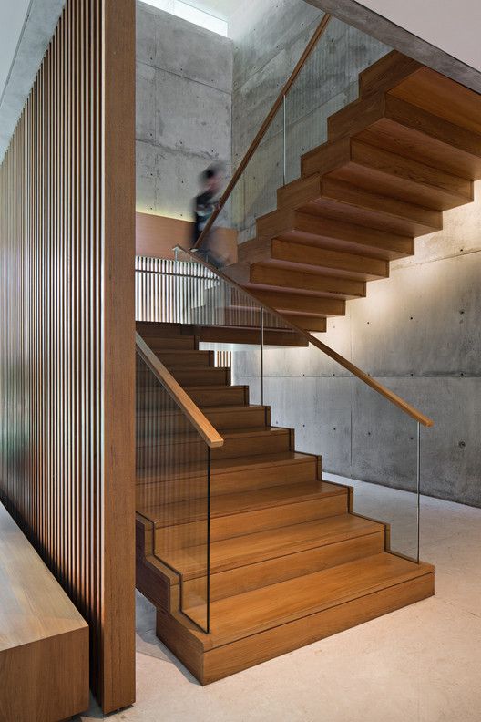 a man riding a skateboard down the side of a wooden stair case next to a set of stairs