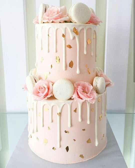 a pink cake with white icing and flowers on top