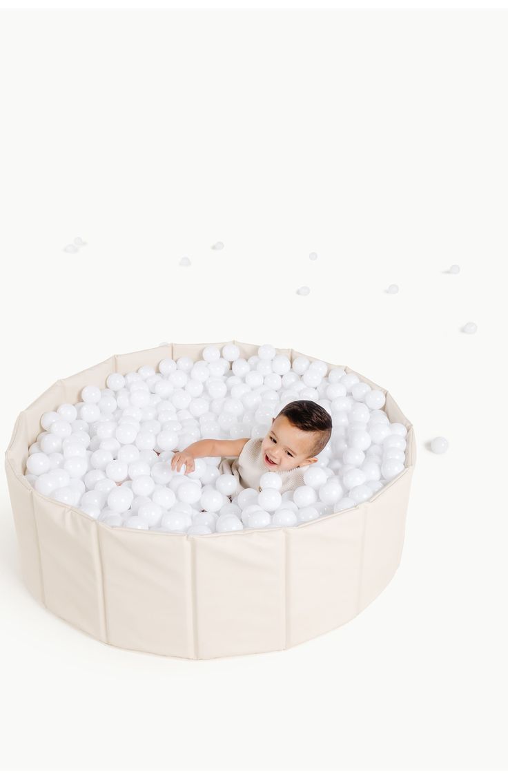 a baby in a ball pool with white balls