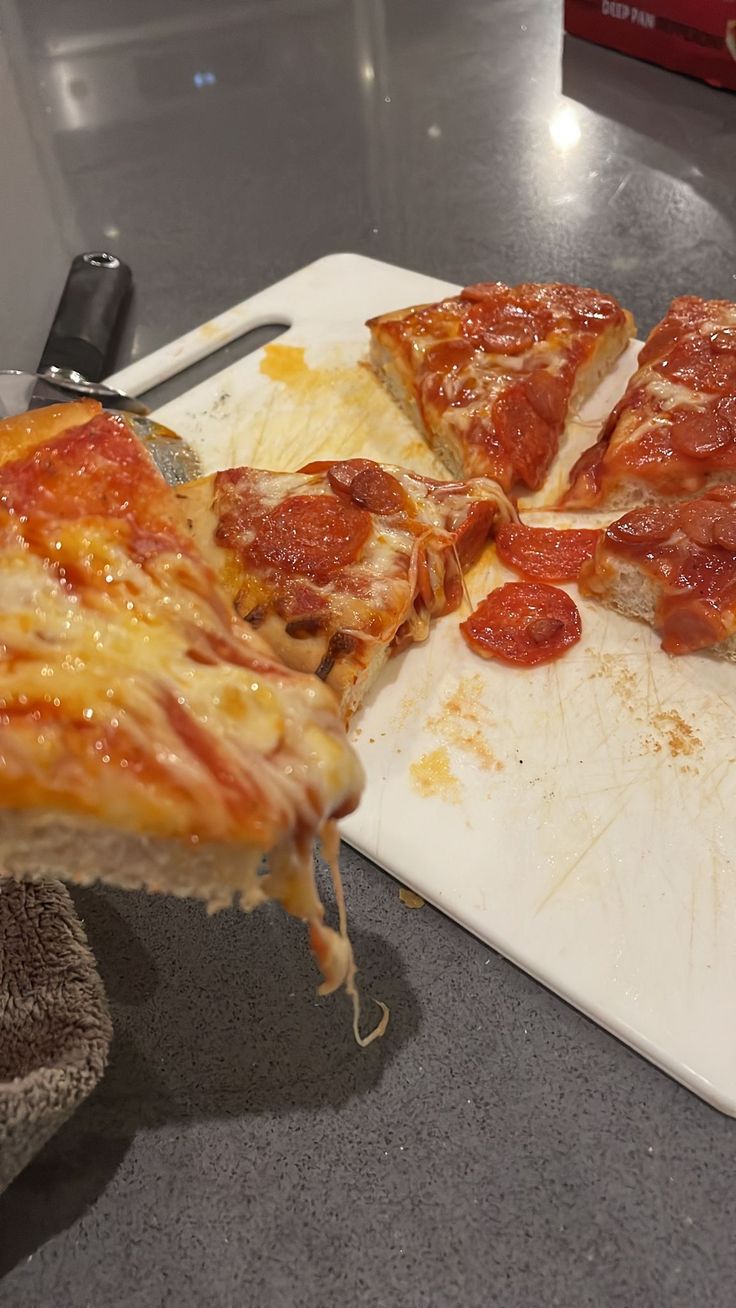 the pizza is being cut into slices on the cutting board and ready to be eaten