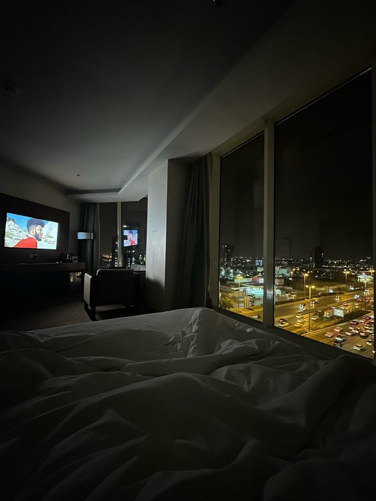 a bedroom with a large window overlooking the city at night