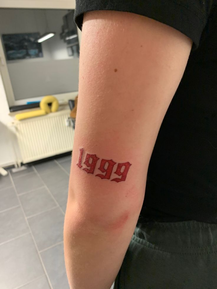 a person with a tattoo on their arm that reads 999, in red ink