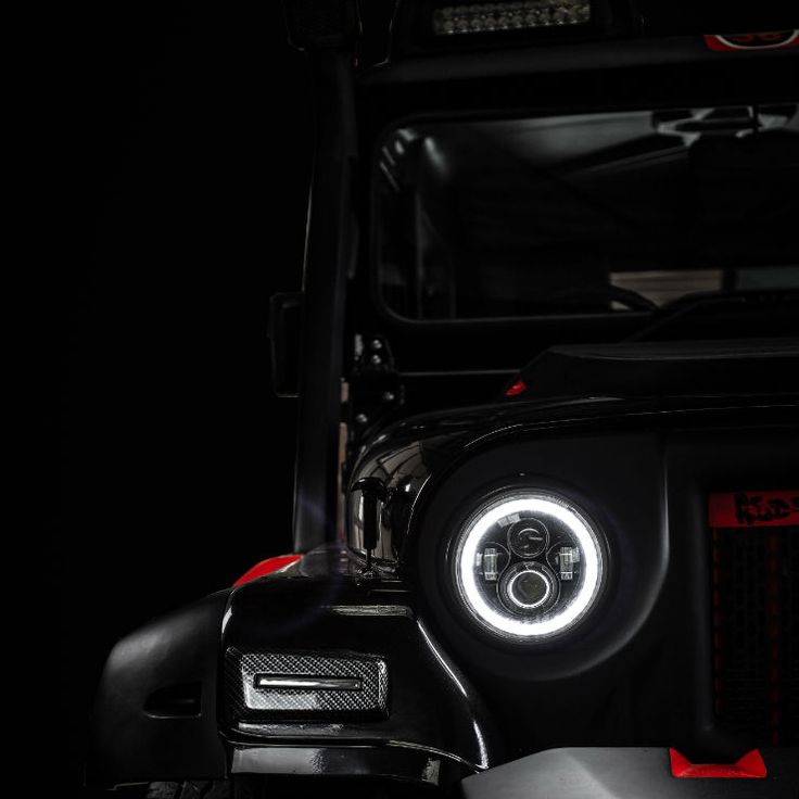 the front lights of a black jeep in the dark