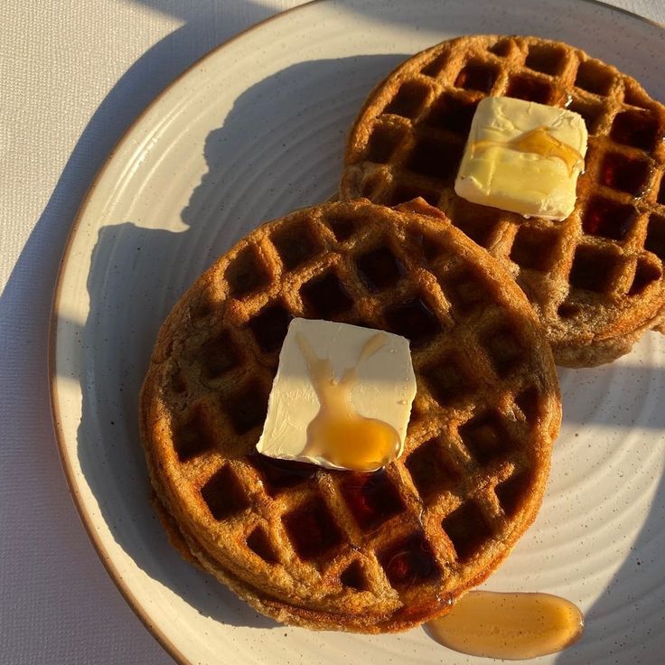 two waffles on a plate with butter and syrup