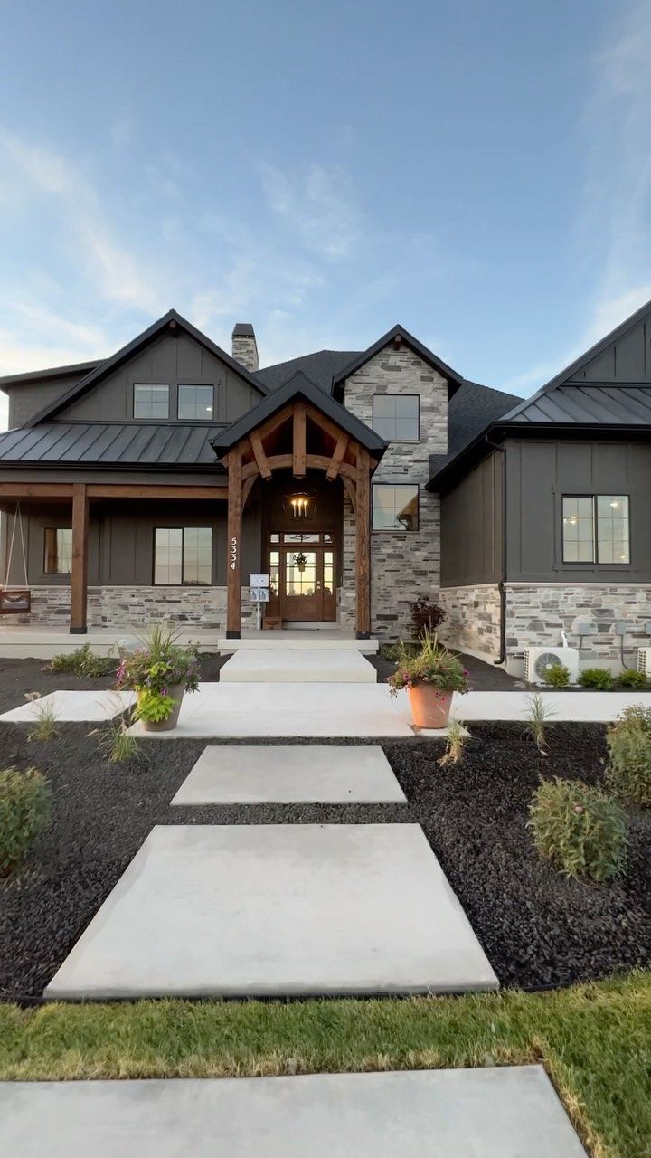 a large house with stone and wood accents on the front door, walkway leading up to it