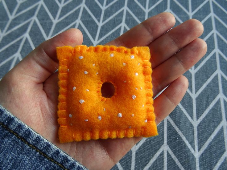 a hand holding a small orange square with white dots