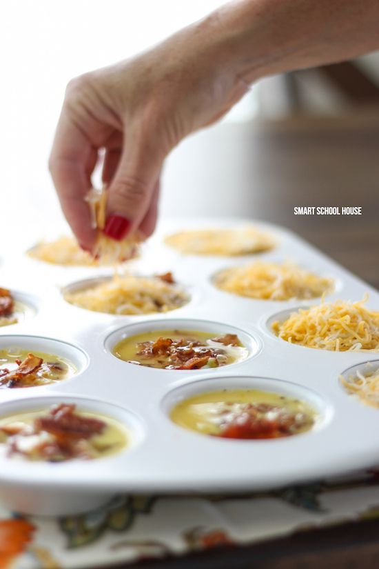 a person dipping cheese on top of some food in a muffin tin with other toppings