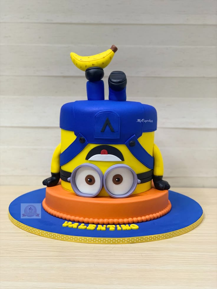 a birthday cake with a despicable minion on top and a banana sticking out of it