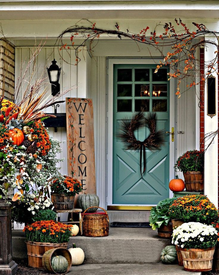 front porch decorated for fall with pumpkins and flowers