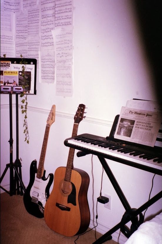 guitars and musical instruments are lined up on the floor in front of a wall with sheet music