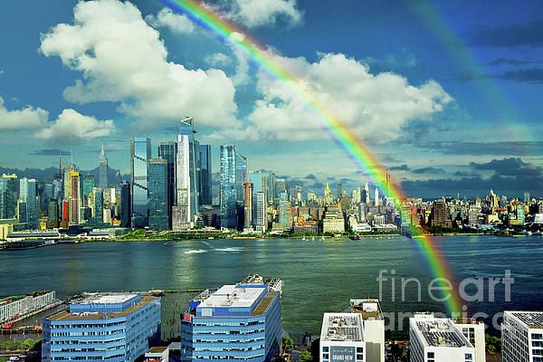 a rainbow in the sky over a city with tall buildings and a large body of water