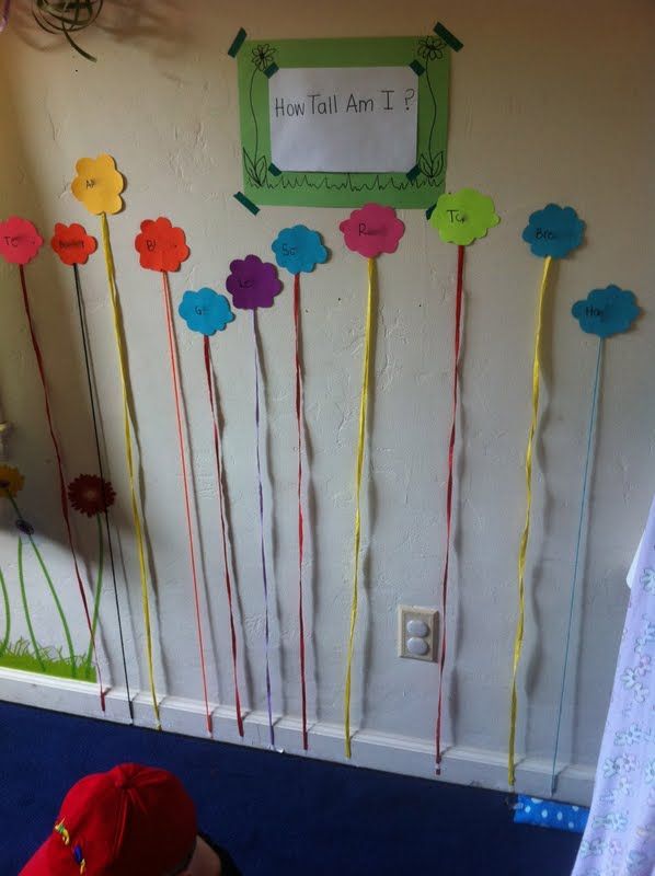 a child is playing in front of a wall decorated with flowers and paper straws